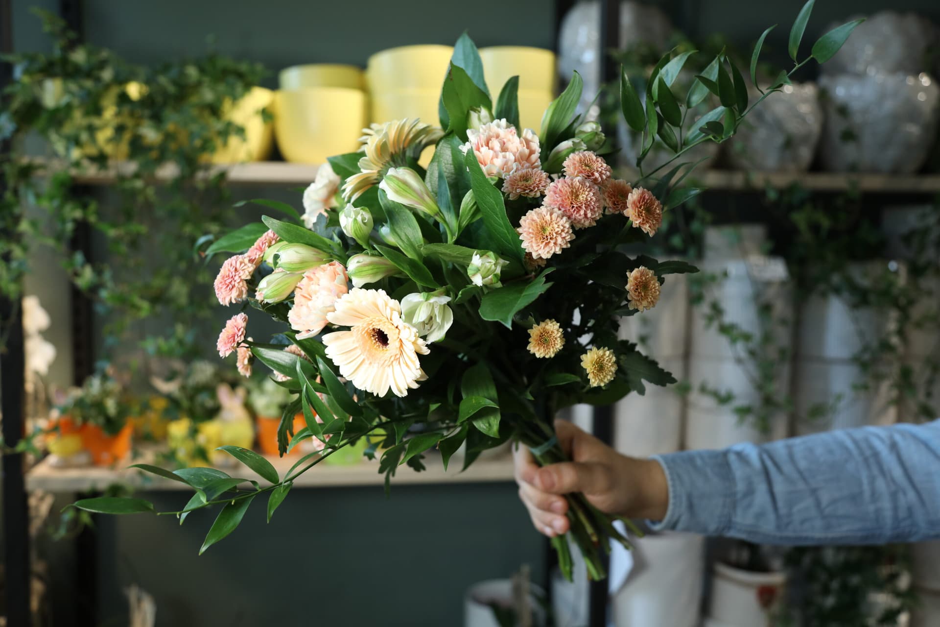Florist håller upp en handbunden bukett i Globens Blommors butik
