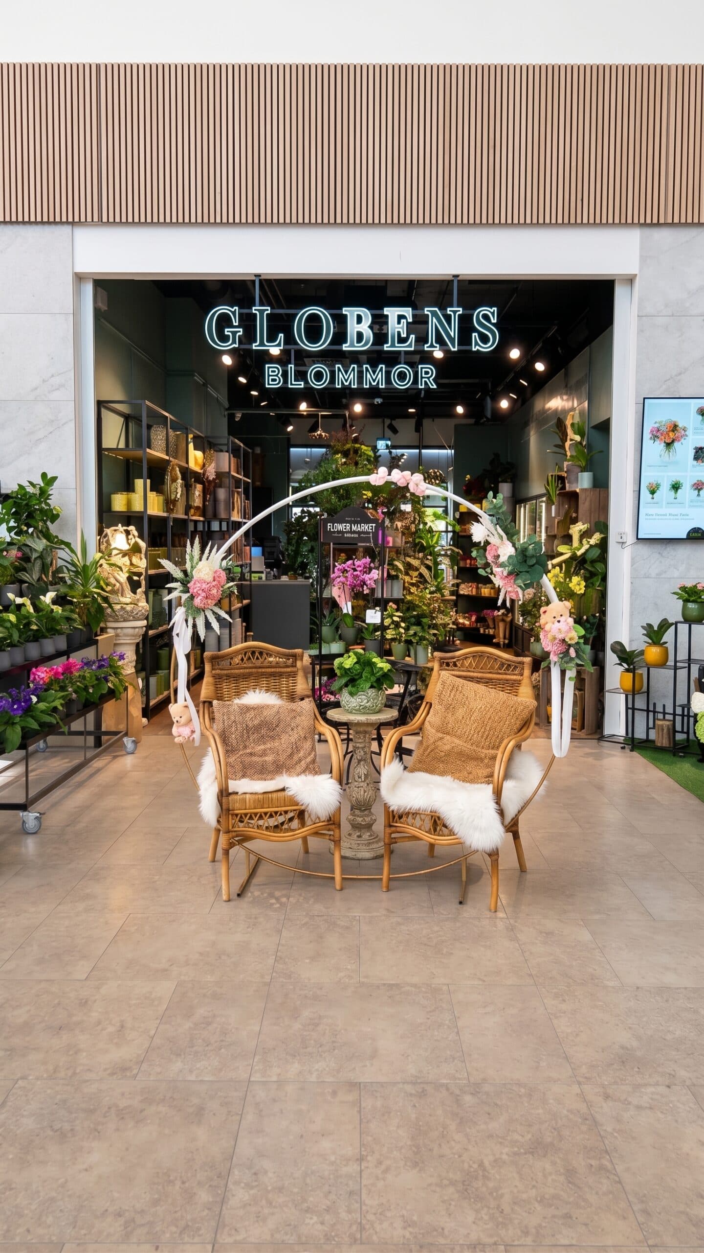 Entrén till Globens Blommor med neonskylt, blomsterhyllor och sittgrupp utanför butiken